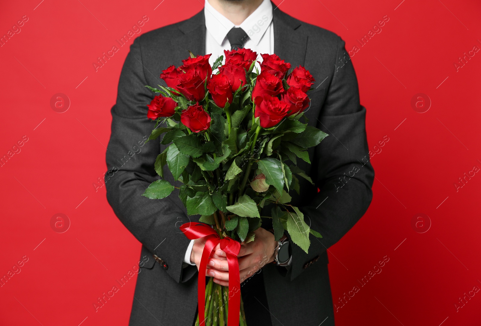 Photo of Happy Valentine's Day. Man with bouquet of roses on red background, closeup