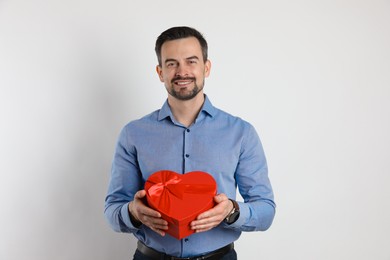 Photo of Happy Valentine's Day. Handsome man with heart shaped gift box on white background