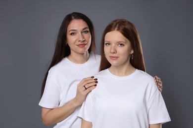 Photo of Portrait of beautiful mother with teenage daughter on grey background