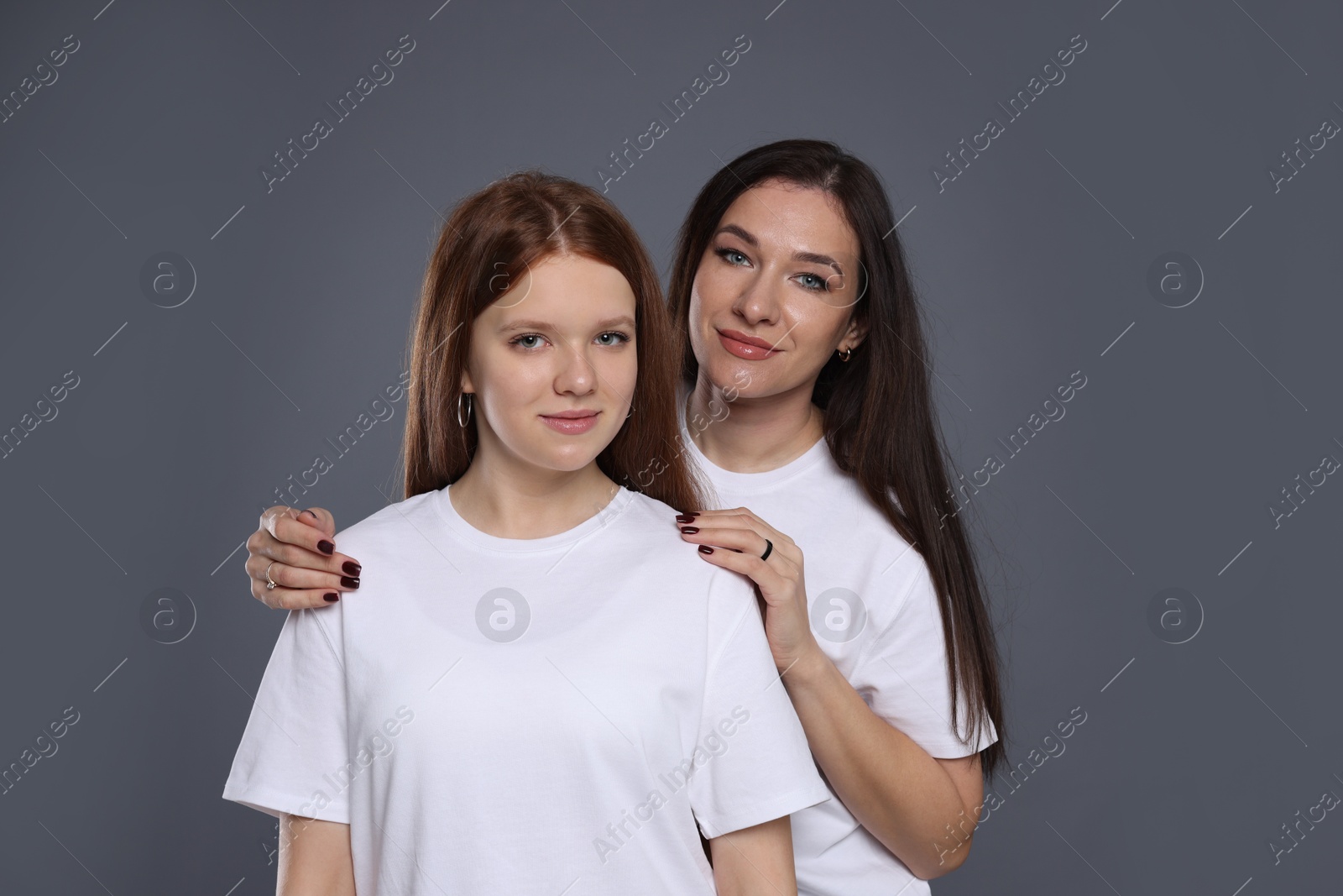 Photo of Portrait of beautiful mother with teenage daughter on grey background