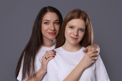 Photo of Portrait of beautiful mother with teenage daughter on grey background