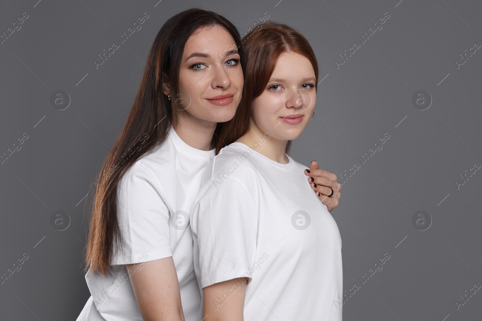 Photo of Portrait of beautiful mother with teenage daughter on grey background