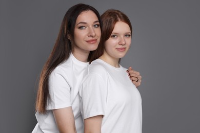 Photo of Portrait of beautiful mother with teenage daughter on grey background