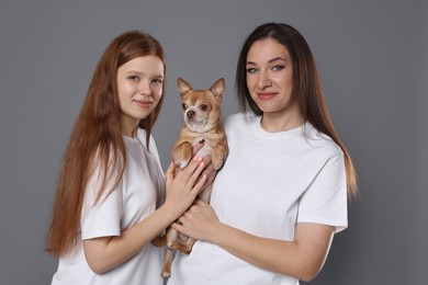 Photo of Family portrait of beautiful mother with teenage daughter and cute Chihuahua dog on grey background