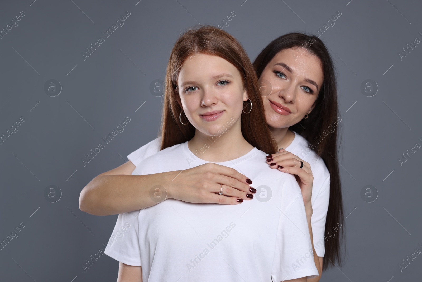 Photo of Portrait of beautiful mother with teenage daughter on grey background