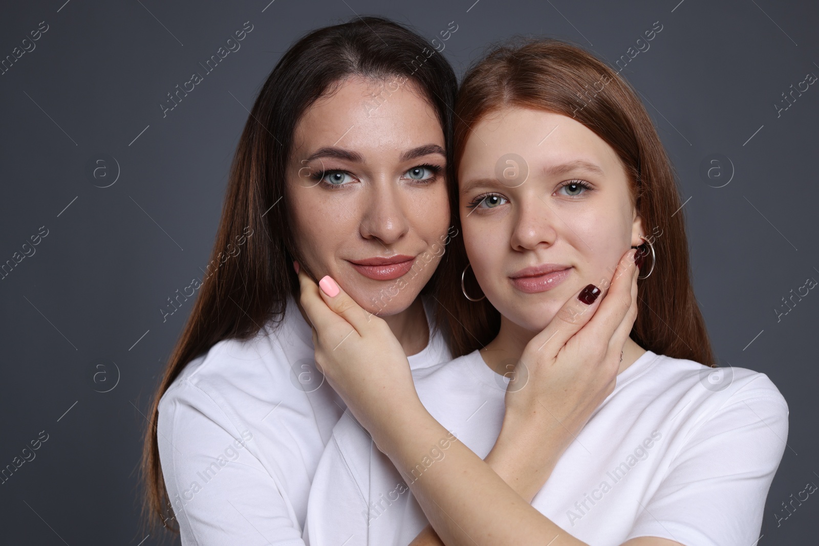 Photo of Portrait of beautiful mother with teenage daughter on grey background