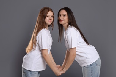 Photo of Portrait of beautiful mother with teenage daughter on grey background