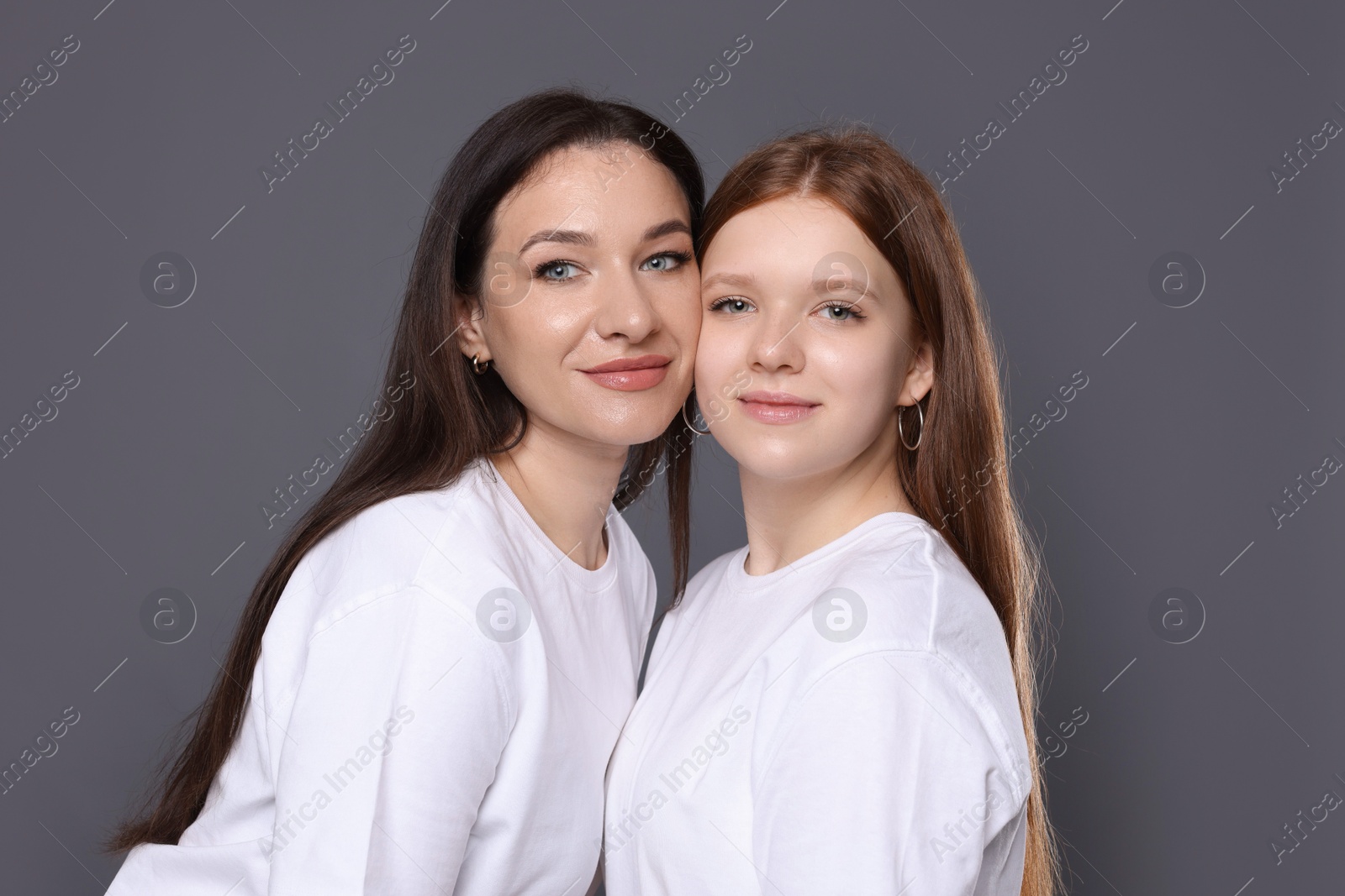 Photo of Portrait of beautiful mother with teenage daughter on grey background