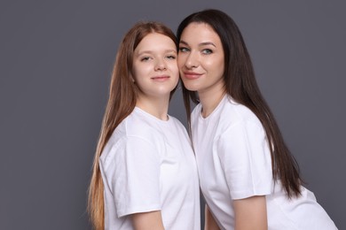 Photo of Portrait of beautiful mother with teenage daughter on grey background