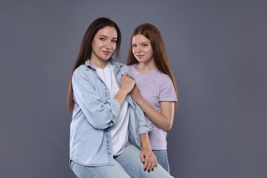 Photo of Portrait of beautiful mother with teenage daughter on grey background