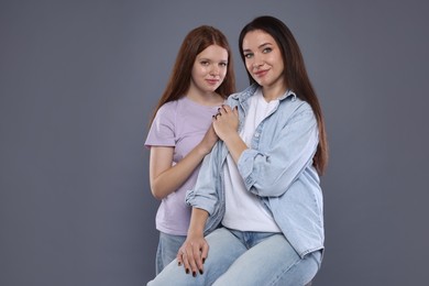 Photo of Portrait of beautiful mother with teenage daughter on grey background