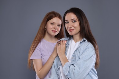 Photo of Portrait of beautiful mother with teenage daughter on grey background