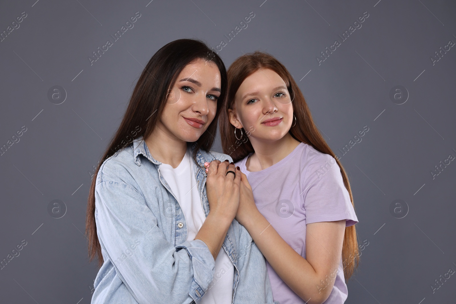 Photo of Portrait of beautiful mother with teenage daughter on grey background