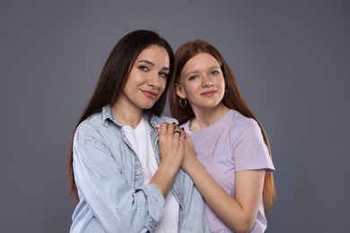 Photo of Portrait of beautiful mother with teenage daughter on grey background