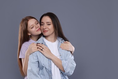 Photo of Family portrait of beautiful mother with teenage daughter on grey background, space for text