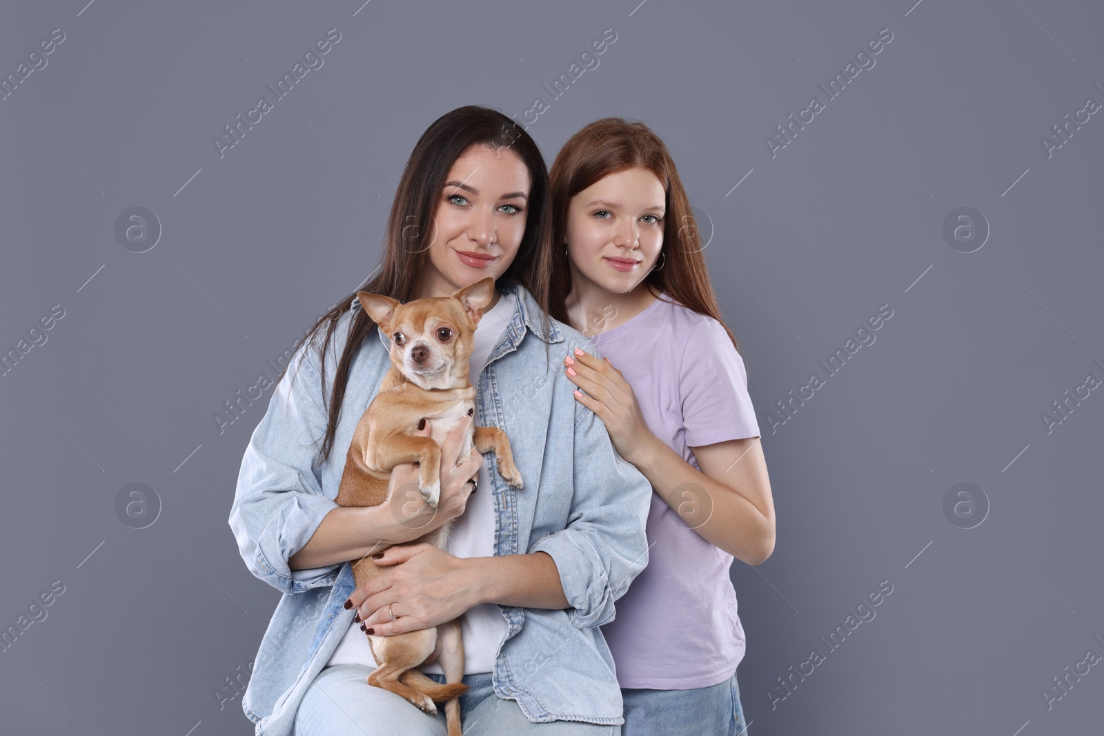 Photo of Family portrait of beautiful mother with teenage daughter and cute Chihuahua dog on grey background