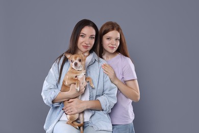 Photo of Family portrait of beautiful mother with teenage daughter and cute Chihuahua dog on grey background