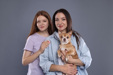 Photo of Family portrait of beautiful mother with teenage daughter and cute Chihuahua dog on grey background