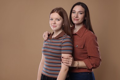 Photo of Portrait of beautiful mother with teenage daughter on dark beige background