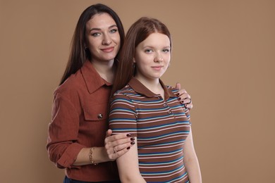 Photo of Portrait of beautiful mother with teenage daughter on dark beige background