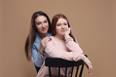 Photo of Portrait of beautiful mother with teenage daughter on dark beige background