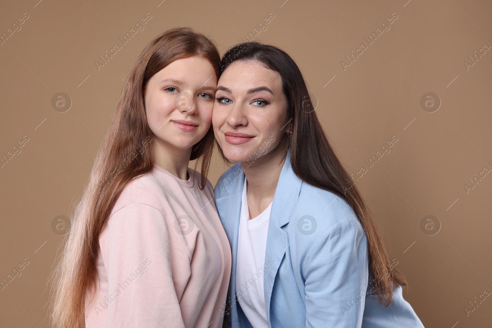 Photo of Portrait of beautiful mother with teenage daughter on dark beige background