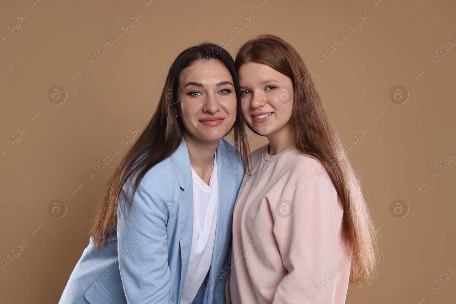 Photo of Portrait of beautiful mother with teenage daughter on dark beige background