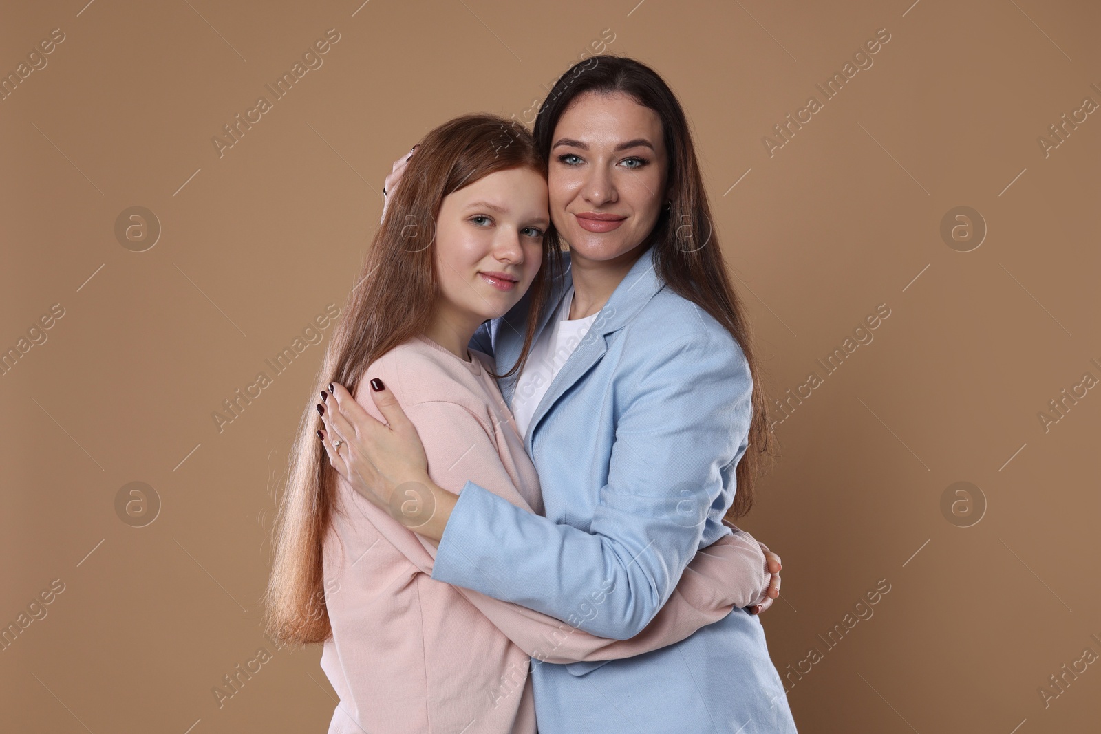 Photo of Portrait of beautiful mother with teenage daughter on dark beige background