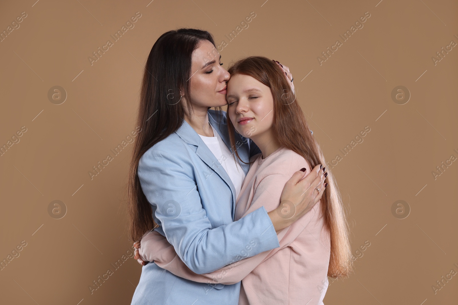 Photo of Portrait of beautiful mother with teenage daughter on dark beige background