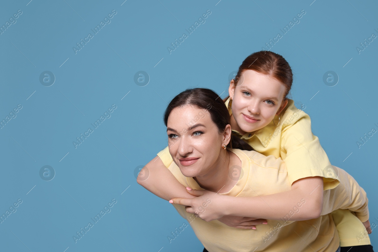 Photo of Portrait of beautiful mother with teenage daughter on light blue background, space for text