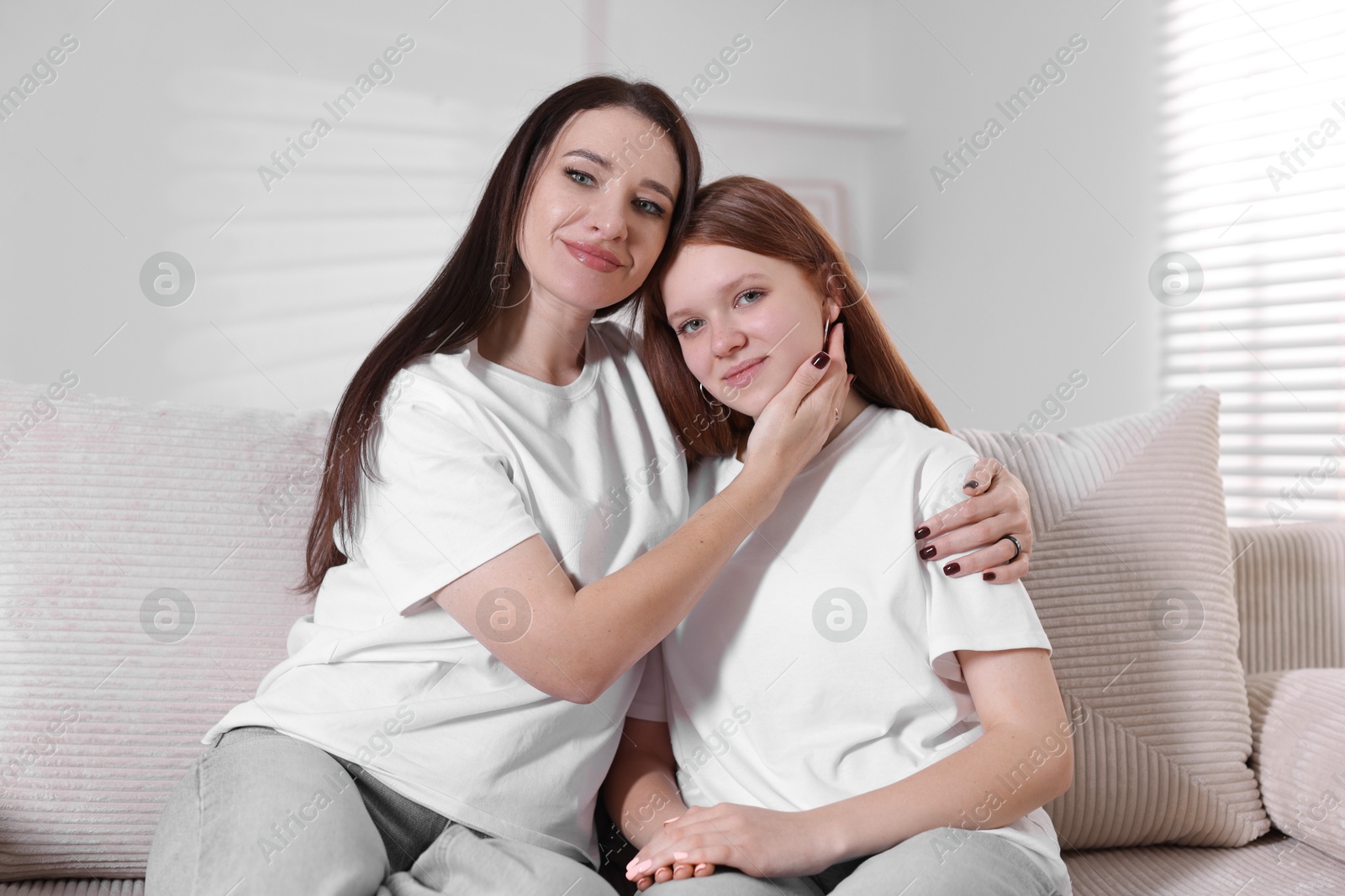 Photo of Portrait of beautiful mother with teenage daughter on sofa at home