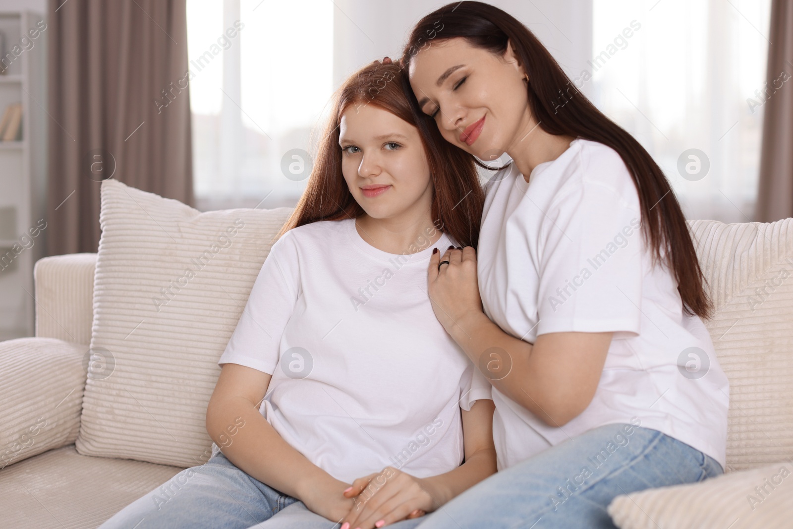 Photo of Portrait of beautiful mother with teenage daughter on sofa at home