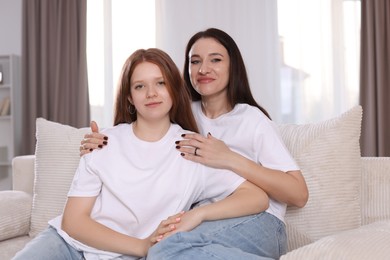 Photo of Portrait of beautiful mother with teenage daughter on sofa at home