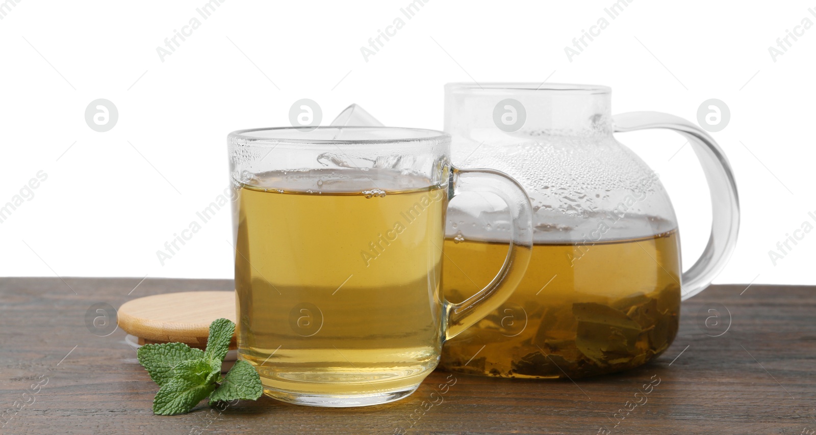 Photo of Aromatic mint tea and fresh leaves on wooden table against white background