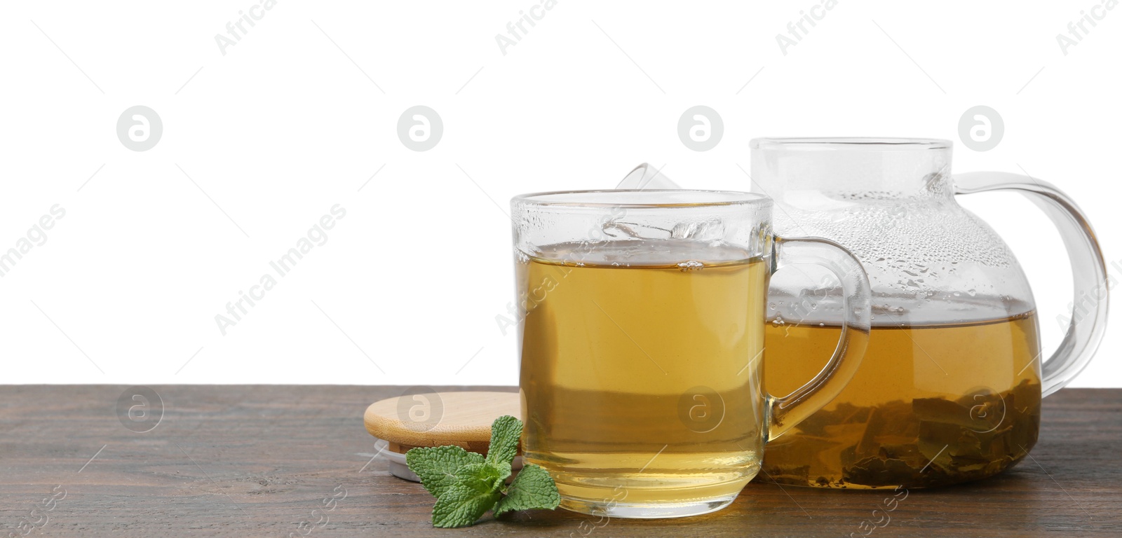 Photo of Aromatic mint tea and fresh leaves on wooden table against white background, space for text