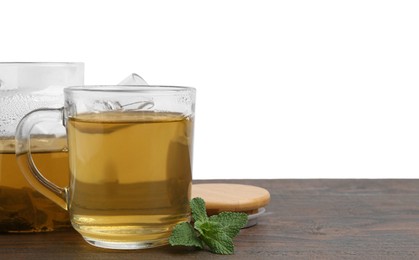 Photo of Aromatic mint tea in glass cup and fresh leaves on wooden table against white background, space for text