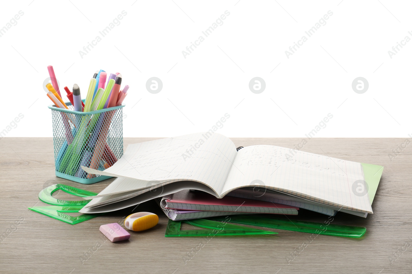 Photo of Doing homework. Copybook with math assignment and different stationery on wooden table against white background