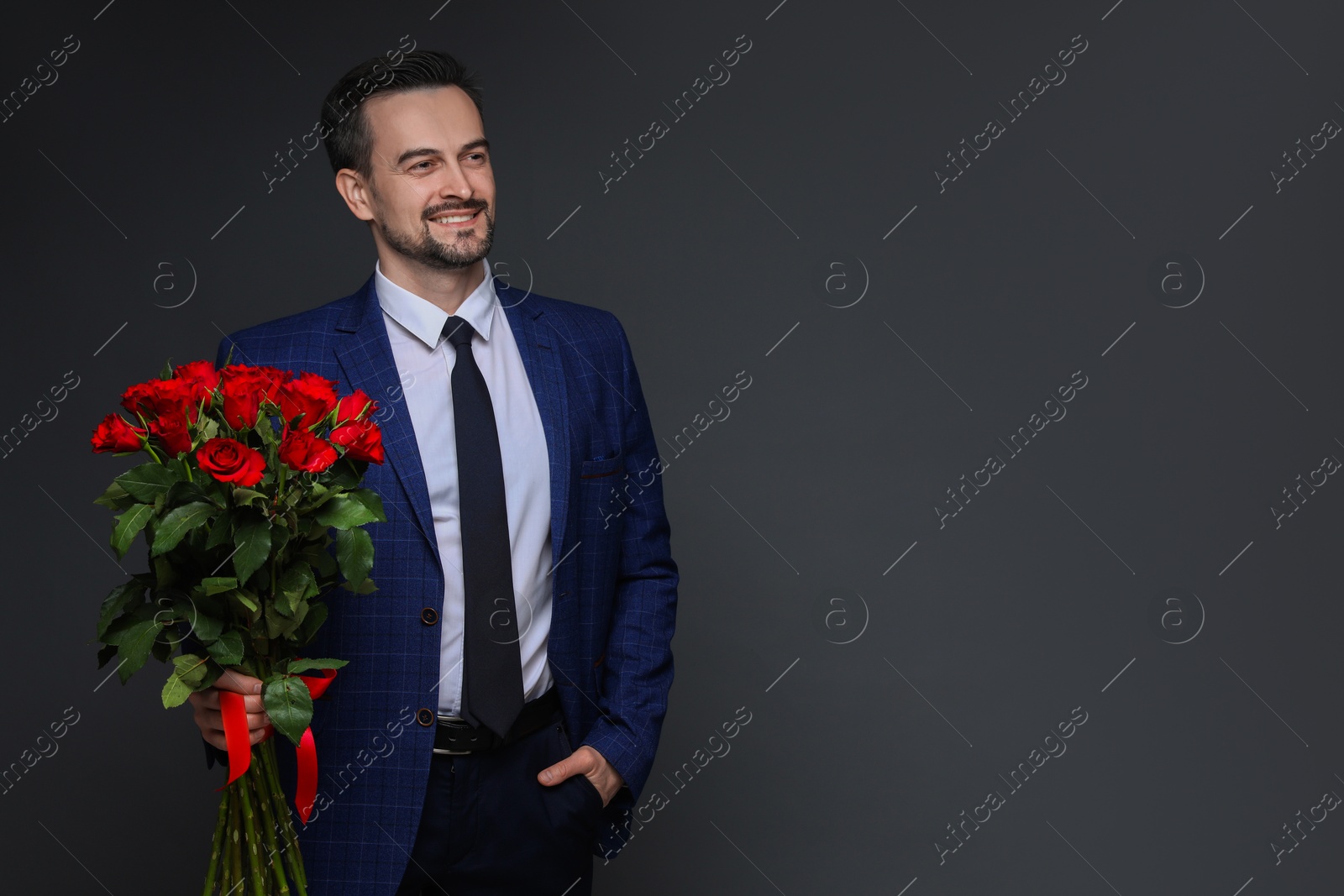 Photo of Happy Valentine's Day. Handsome man with bouquet of roses on grey background. Space for text