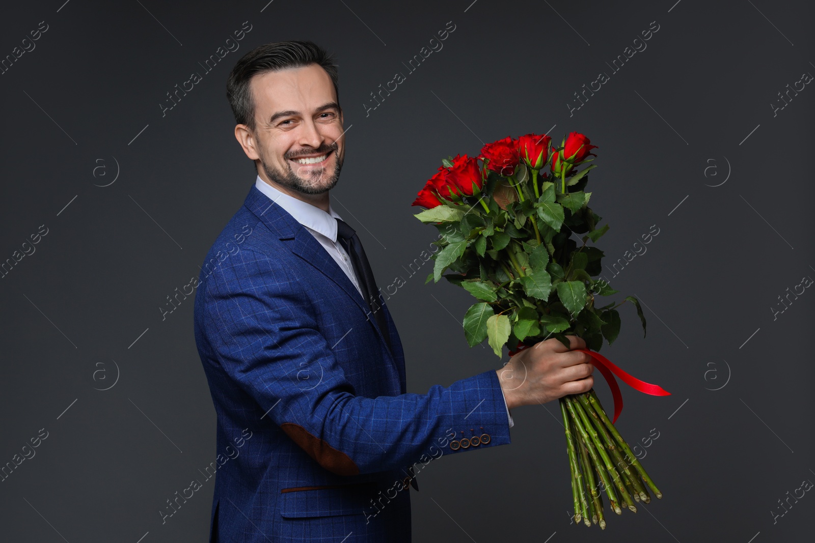 Photo of Happy Valentine's Day. Handsome man with bouquet of roses on grey background