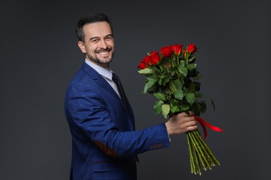 Photo of Happy Valentine's Day. Handsome man with bouquet of roses on grey background