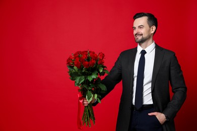 Photo of Happy Valentine's Day. Handsome man with bouquet of roses on red background. Space for text