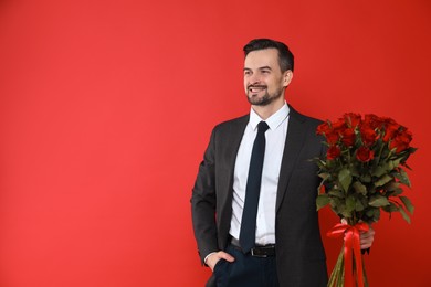 Photo of Happy Valentine's Day. Handsome man with bouquet of roses on red background. Space for text