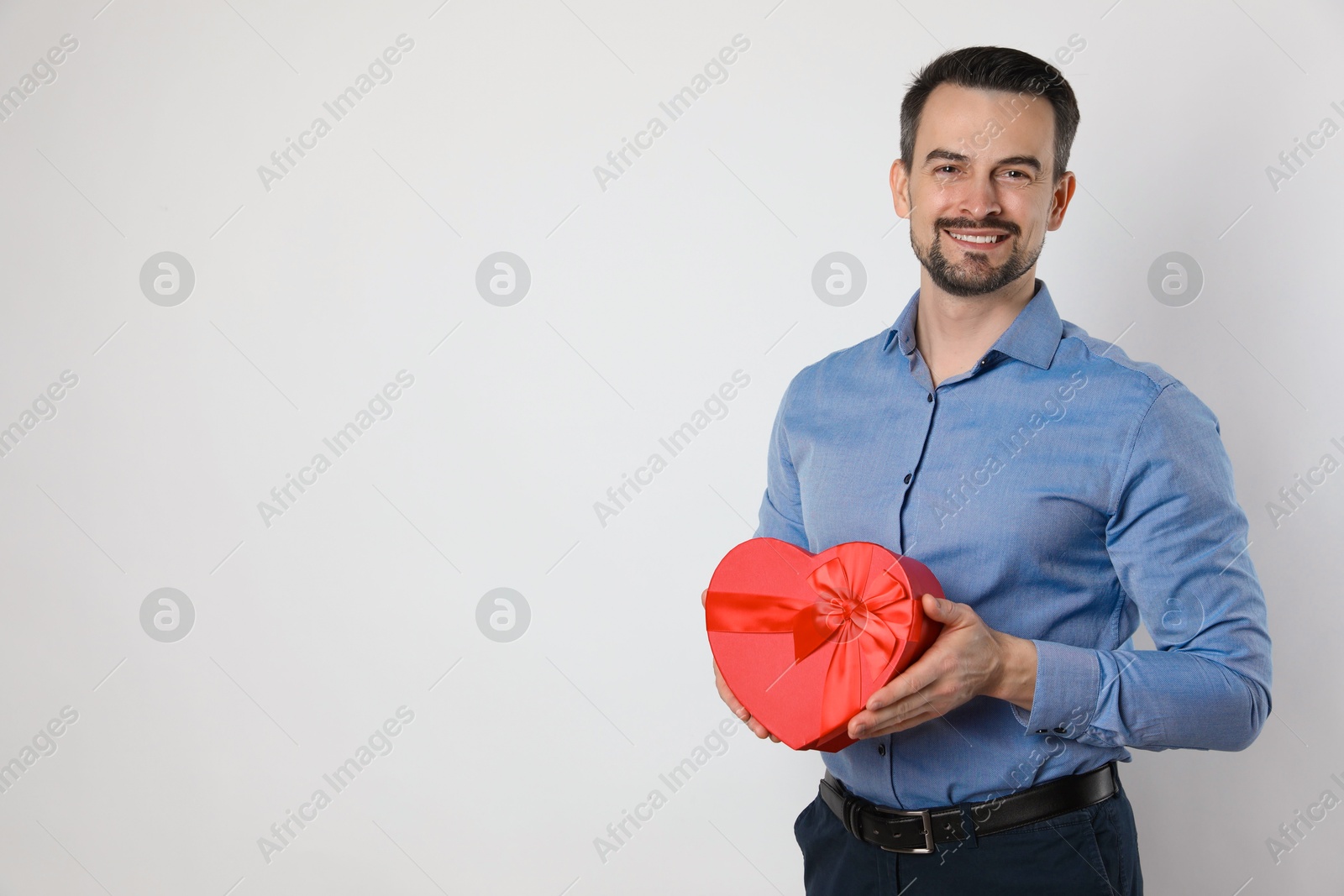 Photo of Happy Valentine's Day. Handsome man with heart shaped gift box on white background. Space for text