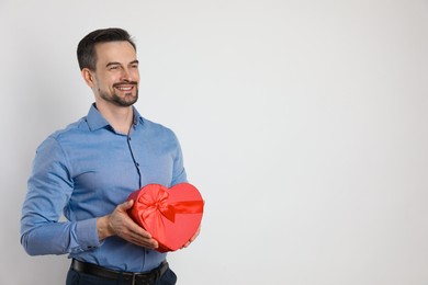 Photo of Happy Valentine's Day. Handsome man with heart shaped gift box on white background. Space for text