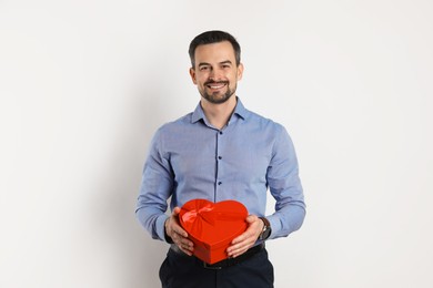 Photo of Happy Valentine's Day. Handsome man with heart shaped gift box on white background