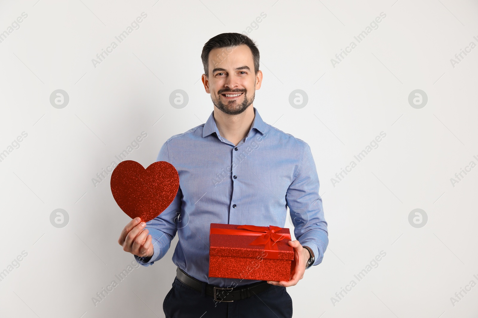 Photo of Happy Valentine's Day. Handsome man with paper heart and gift on white background