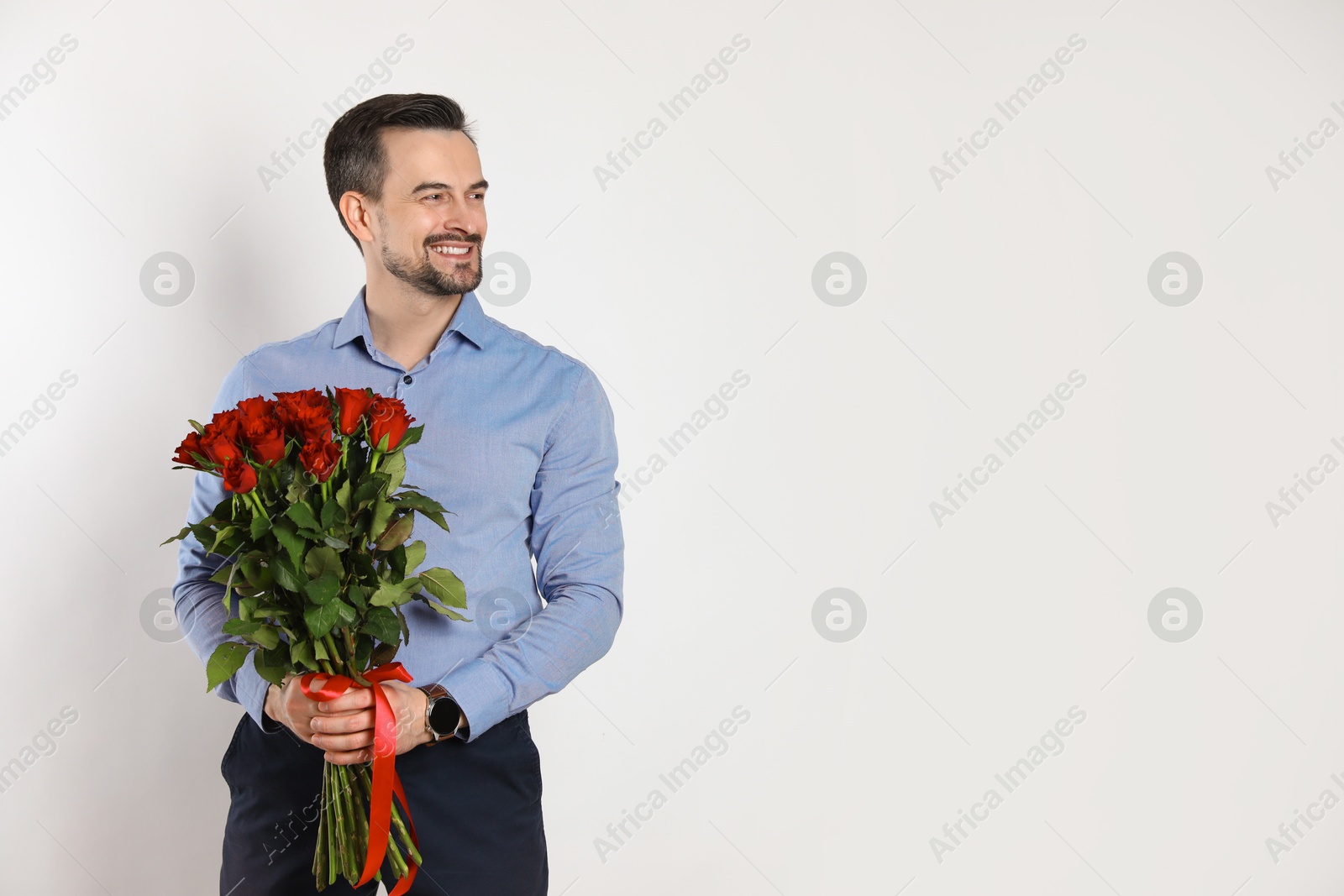 Photo of Happy Valentine's Day. Handsome man with bouquet of roses on white background. Space for text