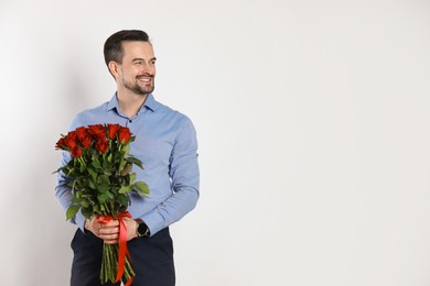 Photo of Happy Valentine's Day. Handsome man with bouquet of roses on white background. Space for text