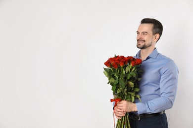 Photo of Happy Valentine's Day. Handsome man with bouquet of roses on white background. Space for text