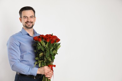 Photo of Happy Valentine's Day. Handsome man with bouquet of roses on white background. Space for text